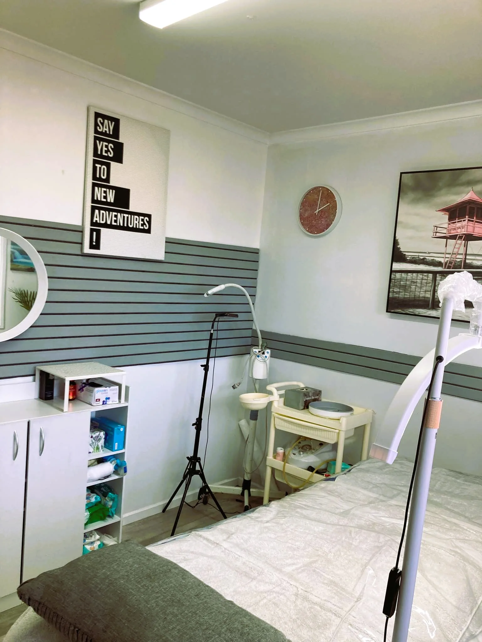 Andée's treatment room — bed with grey bolster, steamer, trolley, supply shelf and round mirror