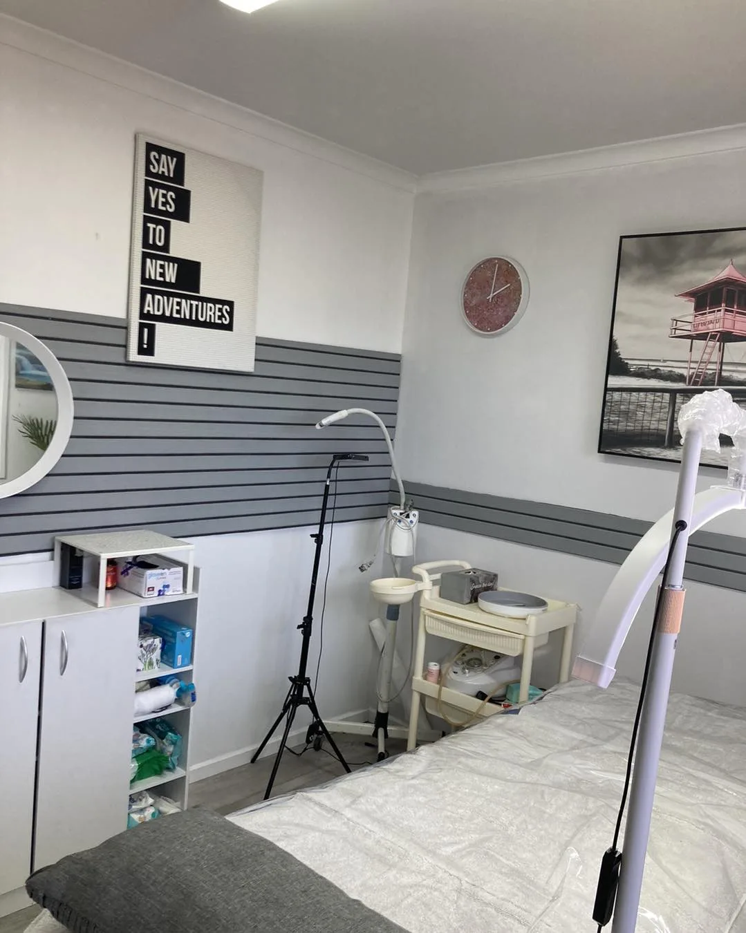 The treatment room from a step back — bed running toward the window, grey-striped wainscot